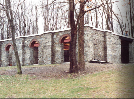 Completed fieldstone foundation before column construction, arched basement windows visible